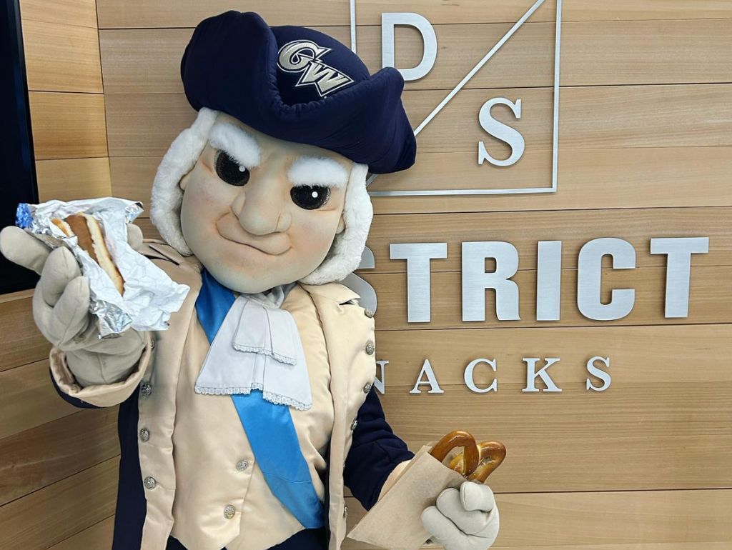 George Washington mascot holds a hot dog and soft pretzel