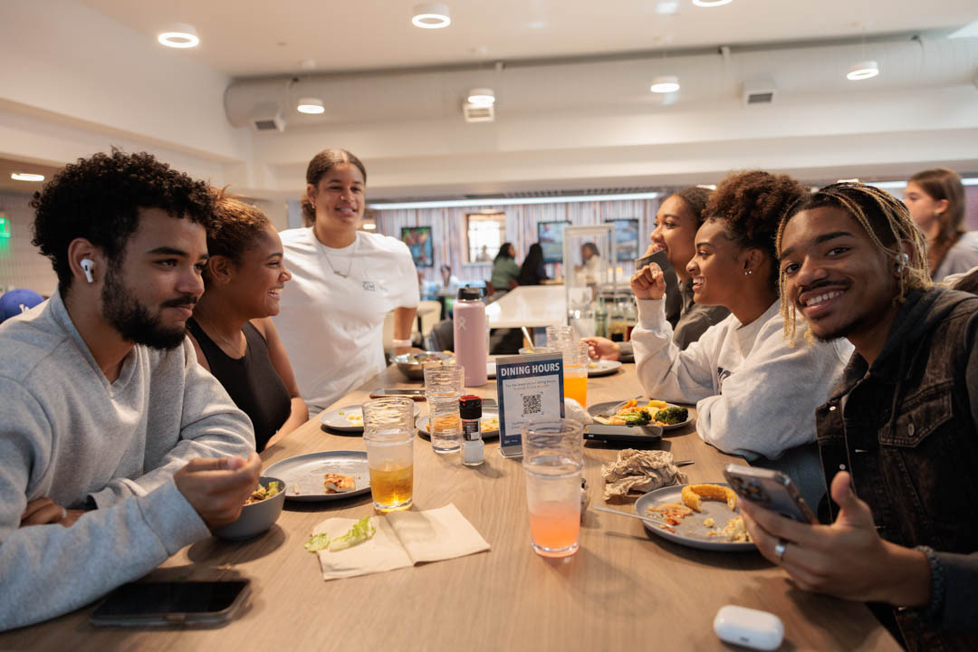 A group of students sit around a table eating in Thurston dining hall