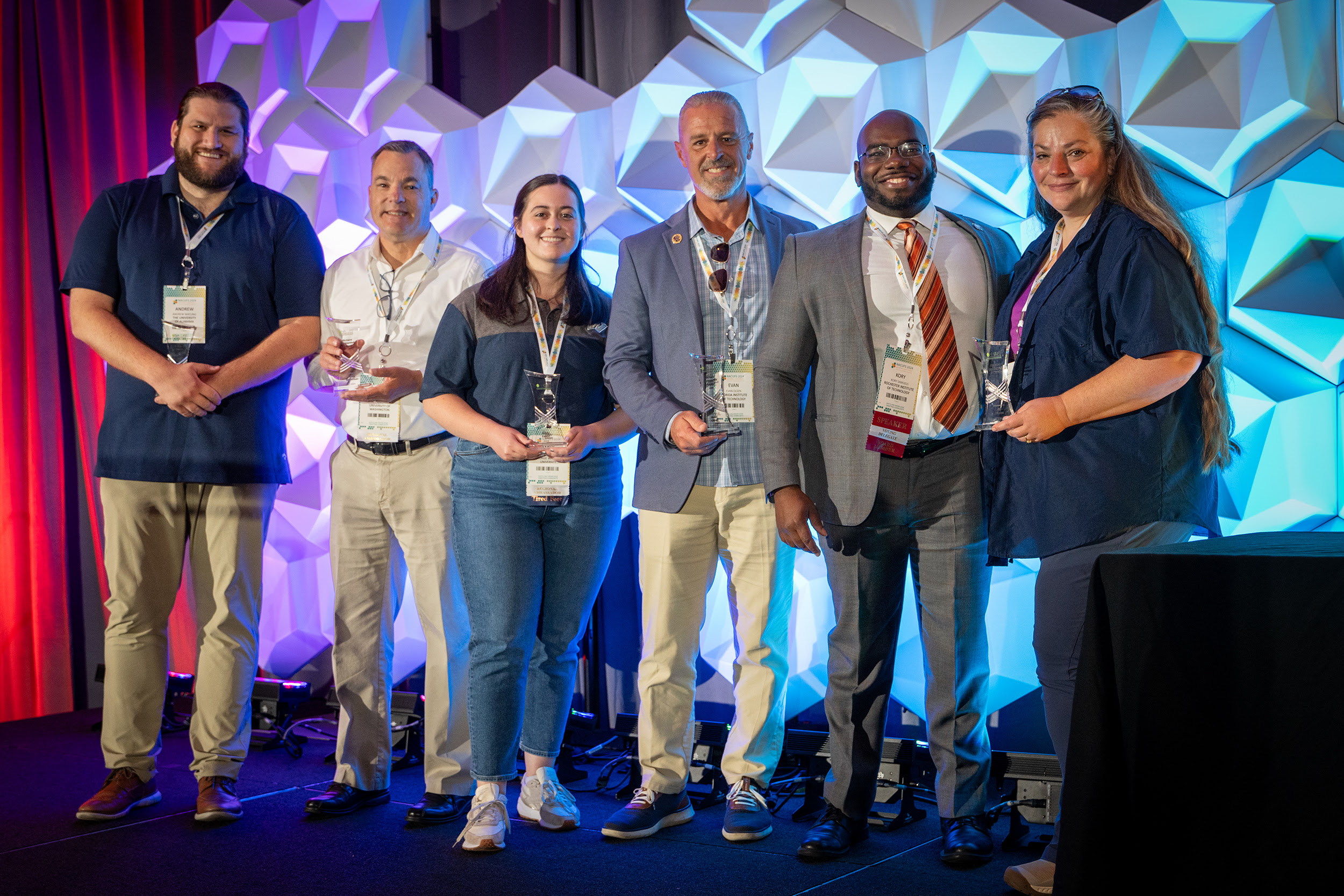 Six Richard Lichtenfelt Award winners stand in a row, smiling with their awards