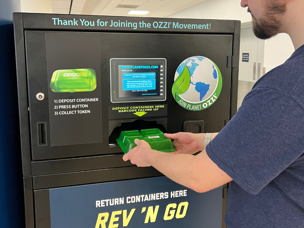 OZZI Step 3: Once you are finished, you will bring the used to-go container back to the dining hall of your choice. At the entrance of each dining hall, you will find a large OZZI receptacle bin. Put your to-go container into the slot upside down so that the machine can scan the container's bar code.